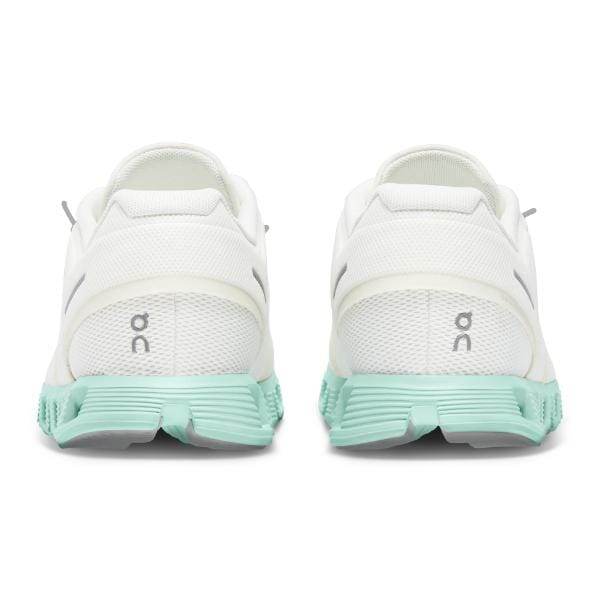 מבט מאחור של זוג נעלי On Cloud 5 לבנות 59.98369 Creek M עם סוליות ירוקות מנטה ולוגו "On Cloud" על העקבים.