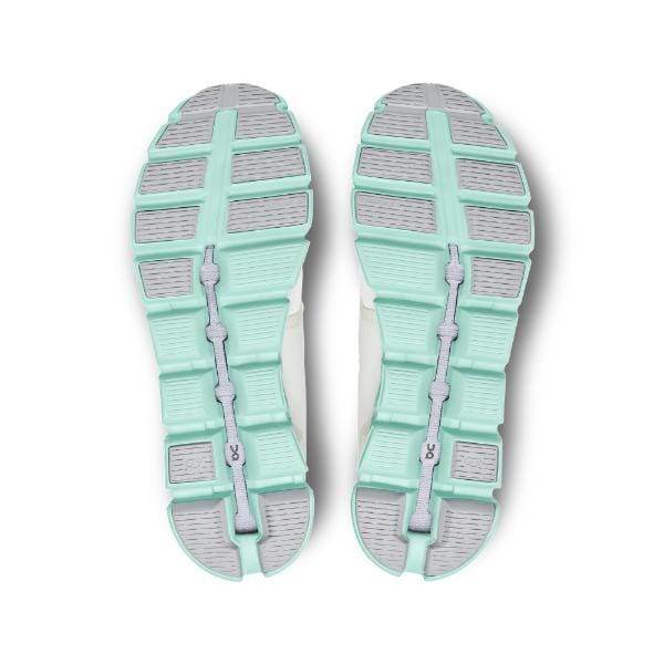 מבט מלמטה של On Cloud 5 59.98369 נעלי ספורט Creek M מאת On Cloud, מציגות סוליות מפולחות בצבע צהבהב ואפור עם חריץ מרכזי ודפוס דריכה מרקם.